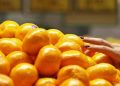 A woman picks up some mandarin oranges at a fruits shop.