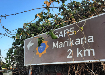 A road sign post shows the distance to the Marikana police station.