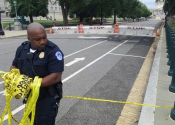 A U.S. Capitol Police officer removes security tape from an area where a man crashed his car into a barricade near the U.S. Capitol and fired shots into the air before killing himself, in Washington, U.S. August 14, 2022.