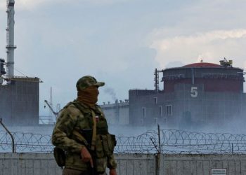 A serviceman with a Russian flag on his uniform stands guard near the Zaporizhzhia Nuclear Power Plant in the course of Ukraine-Russia conflict outside the Russian-controlled city of Enerhodar.
