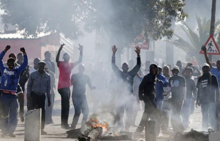 Demonstrators cheer as they tear down a street lamp during a protest against what they said was the government's failure to provide adequate housing facilities and other basic services, in Cape Town's Langa township, July 9, 2014.