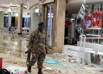 A member of the military inspects damage at a looted mall.