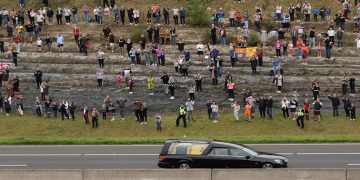People watch the hearse carrying the coffin of Britain's Queen Elizabeth on the M90 motorway, after crossing the Queensferry Crossing, in Queensferry, Scotland, Britain September 11, 2022.