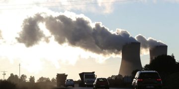 Trucks and cars are seen driving past while smoke rises from the Duvha coal-based power station owned by Eskom, in Emalahleni, in Mpumalanga province, June 3, 2021
