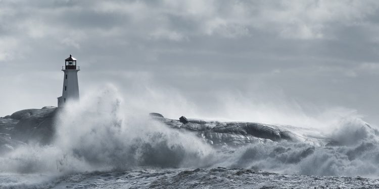 Large waves crash against a lighthouse