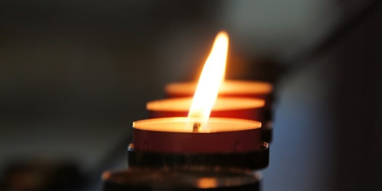 A candle burns at a memorial service