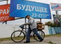 A man walks with his bicycle past banners informing about a referendum on the joining of Russian-controlled regions of Ukraine to Russia, in the Russian-controlled city of Melitopol in the Zaporizhzhia region, Ukraine September 26, 2022.