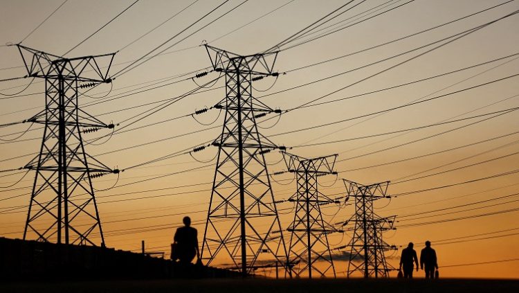 File image: Locals walk past electricity pylons in South African.
