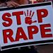 A women holding a placard written Stop Rape