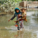 A girl carries her sibling as she walks through stranded flood water, following rains and floods during the monsoon season in Nowshera, Pakistan September 4, 2022. REUTERS/Fayaz Aziz