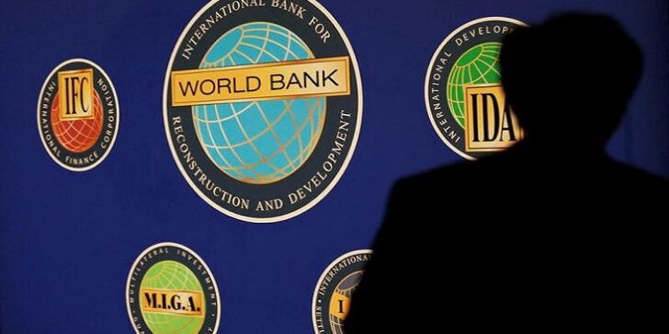 A man is silhouetted against the logo of the World Bank at the main venue for the International Monetary Fund (IMF) and World Bank annual meeting in Tokyo October 10, 2012.