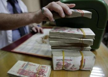 [File Image] A man counts Algerian Dinar banknotes in Algiers.