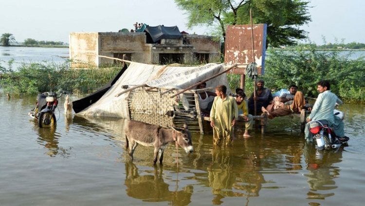 People are seen outside their flooded house, following rains and floods during the monsoon season in Sohbatpur, Pakistan August 28, 2022.