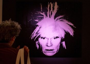 A man examines "Self-Portrait" by Andy Warhol during a media preview at Christie's auction house in New York.