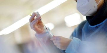 A nurse prepares a booster dose of a COVID-19 vaccine.