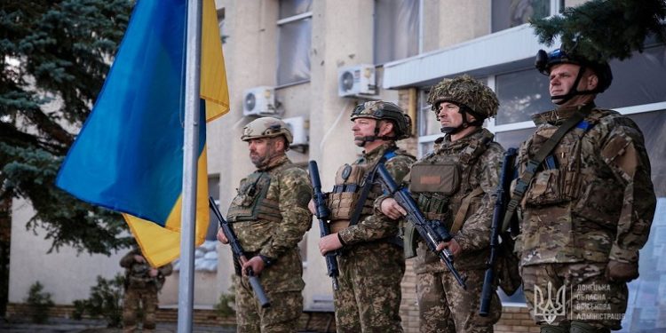 Ukrainian service members attend a flag raising ceremony in the town of Lyman, recently liberated by the Ukrainian Armed Forces, amid Russia's attack on Ukraine, in Donetsk region, Ukraine October 4, 2022.