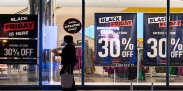 [File Photo] A woman passes by signs advertising sales of Black Friday in the Manhattan borough of New York City, New York, US, November 26, 2021.