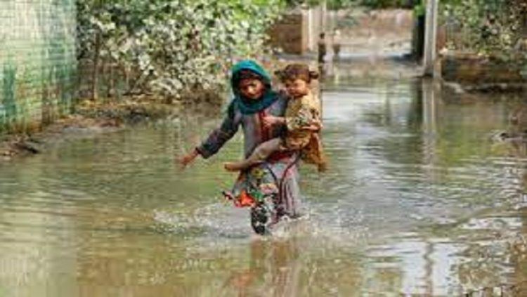A girl carries her sibling as she walks through stranded flood water, following rains and floods during the monsoon season in Nowshera, Pakistan September 4, 2022