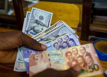 A man trades U.S. dollars for Ghanaian cedis at a currency exchange office in Accra, Ghana