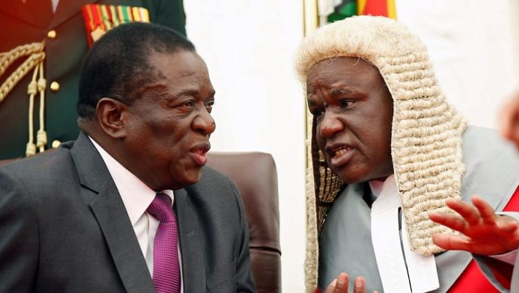 Zimbabwean President Emmerson Mnangagwa talks to the Chief Justice Luke Malaba during the swearing in ceremony of the country's vice presidents at State House in Harare, Zimbabwe, December 28, 2017