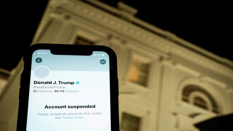 FILE PHOTO: A photo illustration shows the suspended Twitter account of US President Donald Trump on a smartphone and a lit window in the White House residence in Washington, US, January 8, 2021.