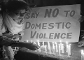 A woman lights a candle at a protest against domestic violence