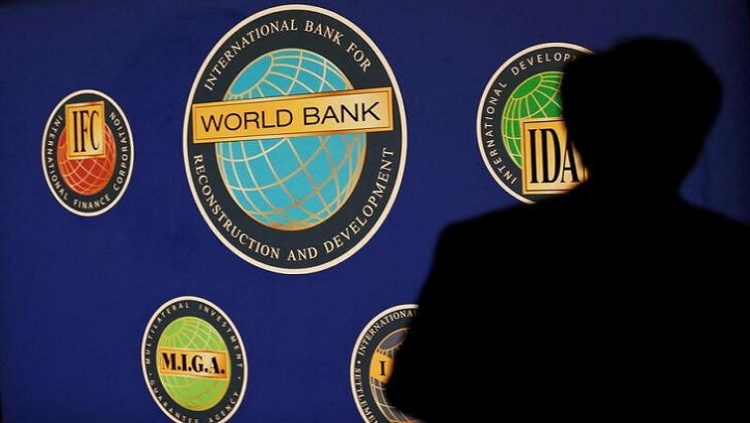 A man is silhouetted against the logo of the World Bank.