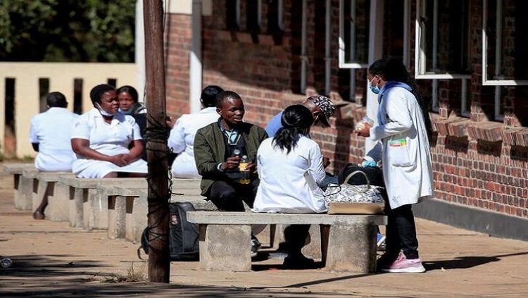 Zimbabwean medical workers sit outside Sally Mugabe Hospital during a strike by state doctors and nurses to press for higher pay, in Harare, Zimbabwe, June 20, 2022.