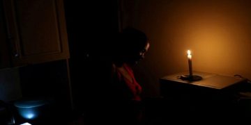 Nokuthula Thwala looks on next to a candle during rolling blackouts in Soweto, South Africa, February 2, 2020.
