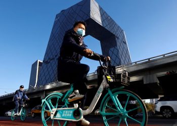 A person rides a bicycle on the street during morning rush hour, following the outbreak of the coronavirus disease (COVID-19), in the Central Business District (CBD) in Chaoyang District, Beijing, China November 21, 2022.