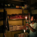 Mulugeta Desalegn, an owner of a convenience store, or "spaza shop", picks an item for a customer as he holds a candle, in Senaone, Soweto, South Africa March 18, 2019.