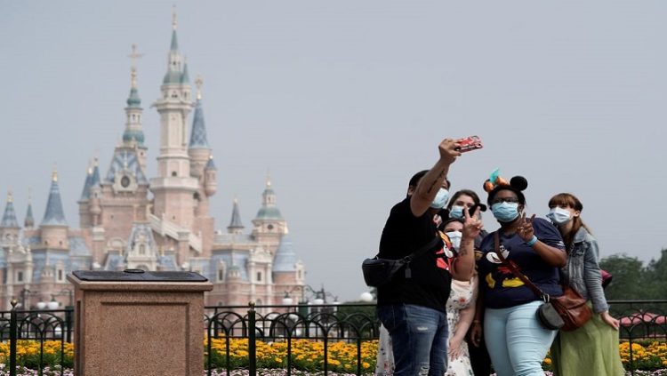 Visitors wearing protective face masks pose for a picture at Shanghai Disney Resort as the Shanghai Disneyland theme park reopens following a shutdown due to the coronavirus disease (COVID-19) outbreak, in Shanghai, China May 11, 2020.