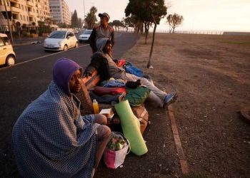 [FILE IMAGE] A group of homeless men take in the last of the days light before seeking a place to sleep on a deserted promenade during the 21-day nationwide lockdown aimed at limiting the spread of coronavirus disease (COVID-19) in Cape Town, South Africa, April 15, 2020.