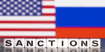 Plastic letters arranged to read "Sanctions" are placed in front the flag colours of US and Russia in this illustration taken February 28, 2022.