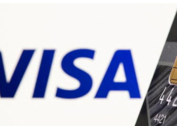 Credit card is seen in front of displayed Visa logo in this illustration taken July 15, 2021.