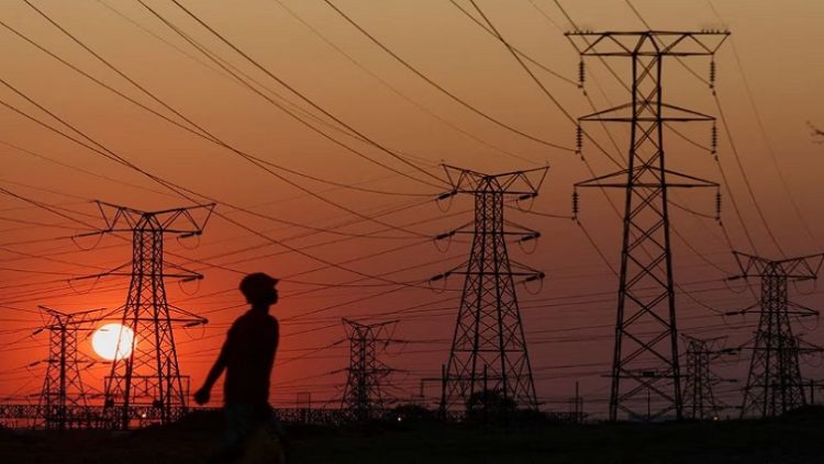 A local walks past electricity pylons during frequent power outages from South African utility Eskom, caused by its aging coal-fired plants, in Orlando, Soweto, South Africa, September 28, 2022.