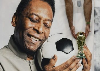 December 2, 2022 Brazil fan holds a replica World Cup trophy in front of a banner of former Brazil player Pele inside the stadium before the match.