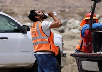 [File photo]A construction worker drinks water in temperatures that have reached well above triple digits.