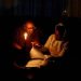 Thandiwe Sithole studies by a candle light while her grandmother Phumzile Sithole looks during one of frequent power outages from South African utility Eskom, South Africa March 9, 2022.