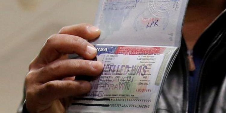 A person holds up their passport showing their visa