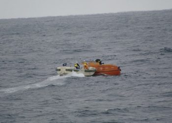 Japan Coast Guard crews check a life boat drifting at sea near the site of a cargo ship that sank off southwestern Japan