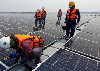 A worker kneels by one of the solar cell panels over the water surface of Sirindhorn Dam in Ubon Ratchathani, Thailand April 8, 2021.
