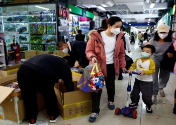 A woman and a child walk past workers sorting toys at a shopping mall in Beijing, China January 11, 2023.