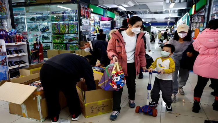 A woman and a child walk past workers sorting toys at a shopping mall in Beijing, China January 11, 2023.