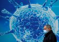 A man wearing a protective face mask walks past an illustration of a virus outside a regional science centre amid the coronavirus disease (COVID-19) outbreak, in Oldham, Britain August 3, 2020.