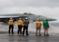 Crew members signal to a F/A-18E Super Hornet fighter jet preparing to take off for a routine flight on board the U.S. USS Nimitz aircraft carrier during a routine deployment to the South China Sea, Mid-Sea, January 27, 2023.