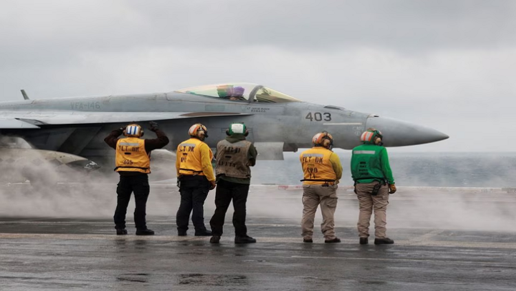 Crew members signal to a F/A-18E Super Hornet fighter jet preparing to take off for a routine flight on board the U.S. USS Nimitz aircraft carrier during a routine deployment to the South China Sea, Mid-Sea, January 27, 2023.