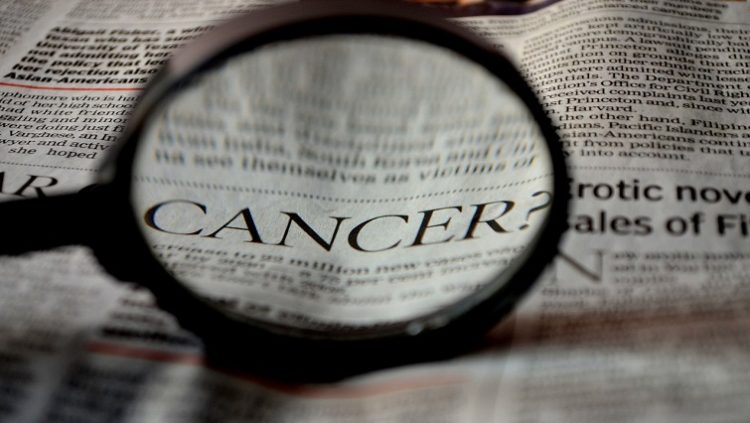 The word 'cancer' highlighted through a magnifying glass