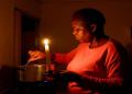 Maria Modiba cooks by a candlelight during one of the frequent power outages from South African utility Eskom, caused by its aging coal-fired plants, in Soweto, South Africa November 11, 2022.