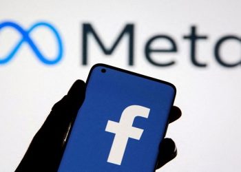 A smartphone with Facebook's logo is seen in front of displayed Facebook's new rebrand logo Meta in this illustration taken October 28, 2021.